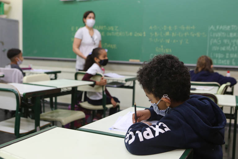Crianças usam máscara de proteção em sala de aula de uma escola pública em São Paulo