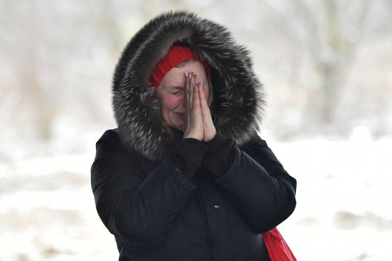 Mulher aguarda parentes atravessarem ponte destruída ao deixarem a cidade de Irpin