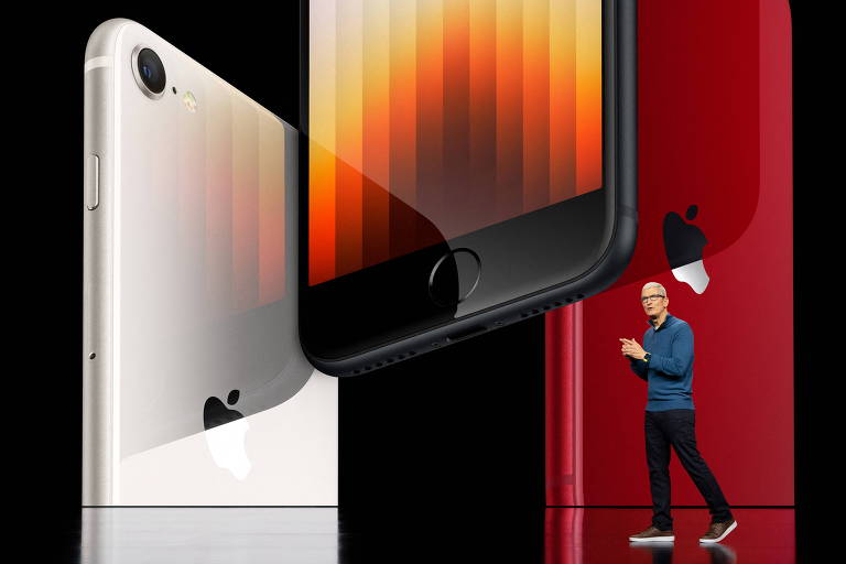Presidente-executivo da Apple, Tim Cook, durante evento da Apple em março. Cook veste calça preta e camisa azul. Na tela detrás dele, estão iPhones SE, linha de entrada da Apple, com rede 5G, um dos lançamentos da ocasião.