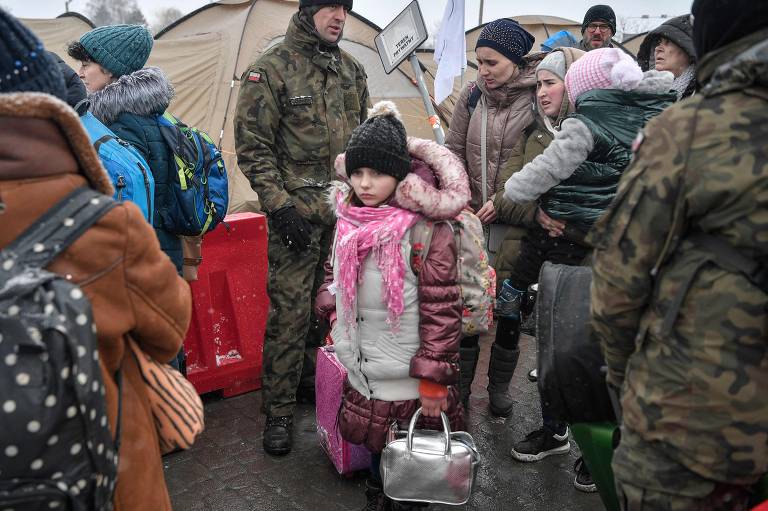 Um grupo de refugiados é recebido por voluntários  na fronteira com a Polônia, em Medyka