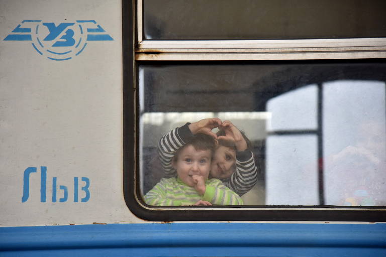 Crianças acenam de trem que leva transporta refugiados em Lviv