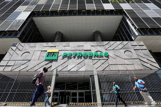 FILE PHOTO: People walk in front of the headquarters of Petrobas in Rio de Janeiro