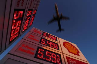 FILE PHOTO: Aircraft flies over gasoline price signs in California