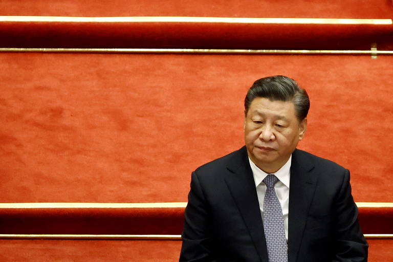 O líder chinês, Xi Jinping, em conferência na China de terno sobre fundo vermelho