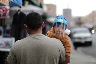 A man carries a baby wearing a mask to protect against the coronavirus disease (COVID-19), in Los Angeles