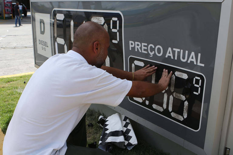 Funcionário de posto de combustíveis, em São Paulo, altera painel de preços nesta quinta-feira (10)