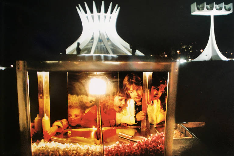Crianças observam o interior de um carrinho de pipoca dianta da catedral metropolitana em Brasília em 2003 
