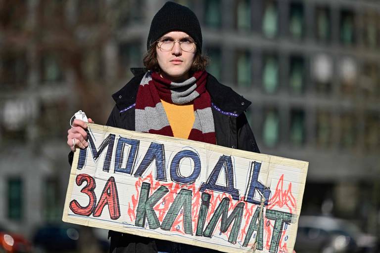 Ativista segura um cartaz com os dizeres "Juventude pelo Clima" em uma manifestação contra a guerra na Ucrânia