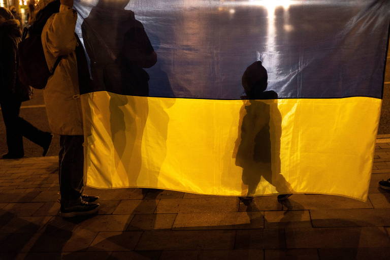 Sombra de garoto projetada em bandeira da Ucrânia em protesto na cidade de Mariupol dois dias antes do início da guerra[