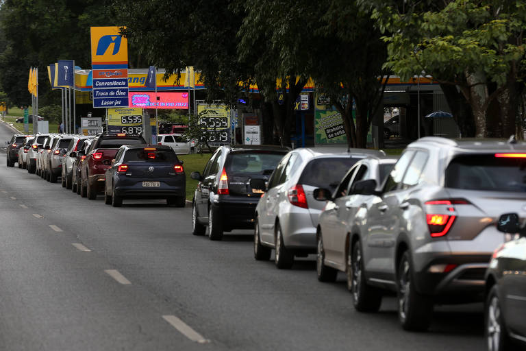 Imagem mostra uma fila de automóveis para abastecer em um posto de gasolina, em Brasília. Eles se enfileiram na faixa da direita da via, enquanto as outras estão vazias. São onze os carros que aparecem na foto. 