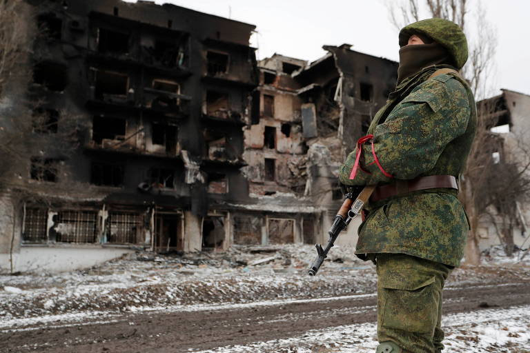 Soldado das forças pró-Rússia em frente a prédio residencial destruído, na região de Donetsk, na Ucrânia