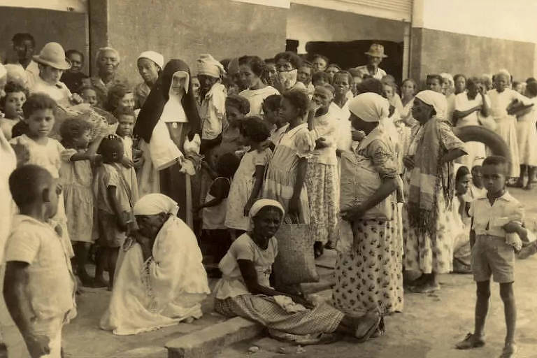 Fotografia em preto e branco mostra irmã Dulce e um grupo de mulheres e crianças negras