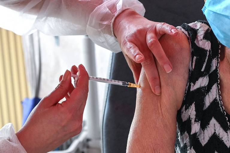 Enfermeira aplica a vacina contra a Covid-19 em braço de idosa