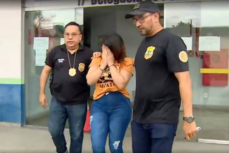 Mulher com mãos no rosto anda ao lado de dois policiais