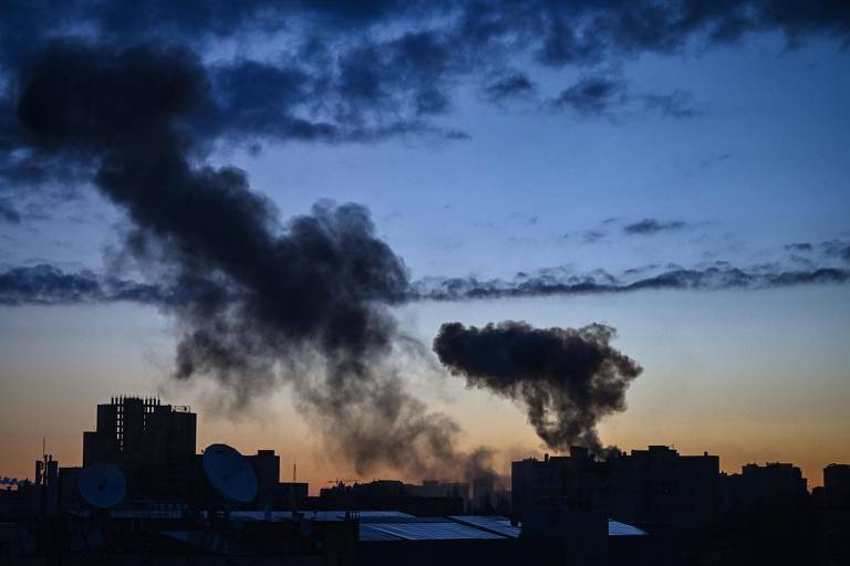 Fumaça sobe no horizonte após ataque russo à periferia de Kiev, que está sob toque de recolher