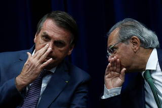 Brazil's President Jair Bolsonaro talks with Brazil's Economy Minister Paulo Guedes during the launch ceremony of the regulatory model of the National Institute of Metrology, Standardization and Industrial Quality (INMETRO) in Brasilia,