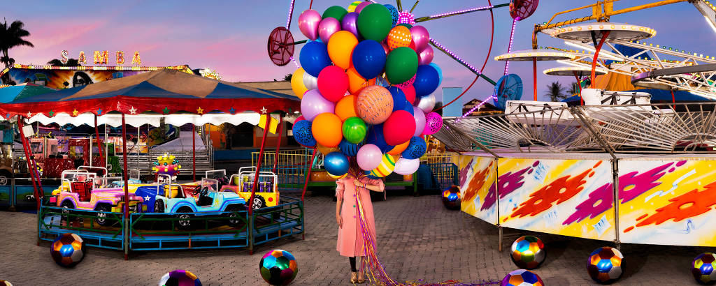 uma criança num parque de diversão segura vários balões ultracoloridos
