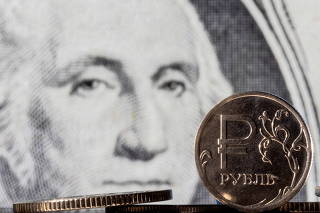 Illustration shows Russian Rouble coins are seen in front of displayed U.S. Dollar banknote