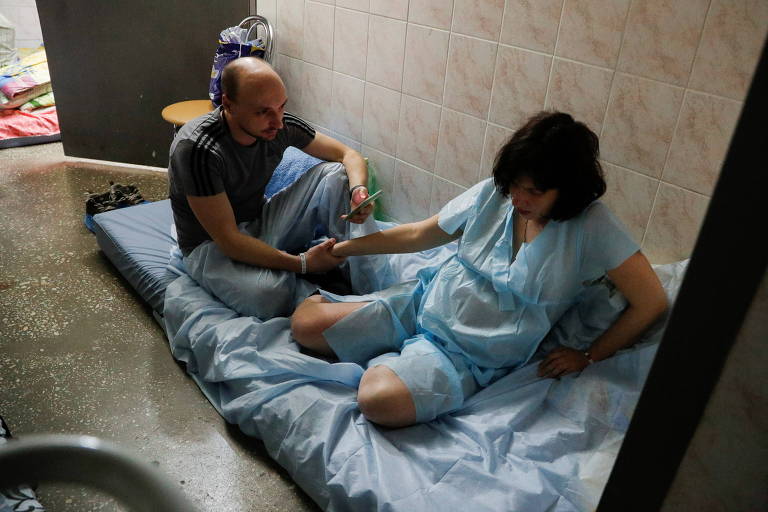 Homem ajuda a mulher grávida enquanto aguardam o parto no porão de uma clínica perinatal em Kiev, na Ucrânia, devido aos ataques da Rússia