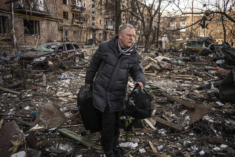 Morador de prédio atingido por ataque russo em Kiev carrega pertences que conseguiu resgatar