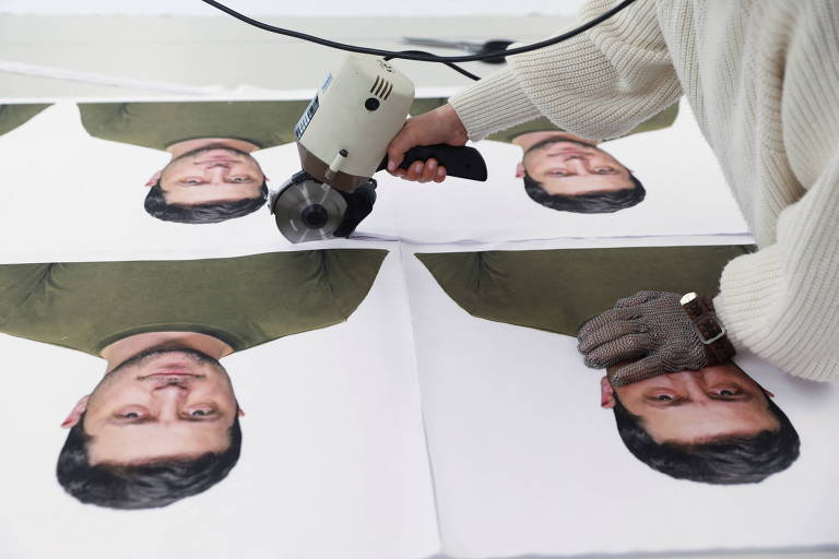 Recortes de tecido com o rosto de Volodimir Zelenski são dispostos em uma mesa