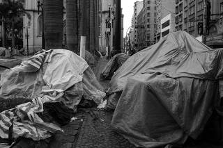 Morador de rua na chuva com barracas