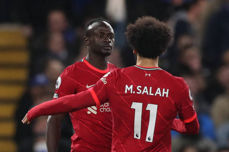 Sadio Mané, do Liverpool, observa o colega de ataque, o egipcio Mohamed Salah, que veste a camisa 11, depois de gol do senegalês diante do Chelsea na Premier League; o uniforme dos dois é vermelho