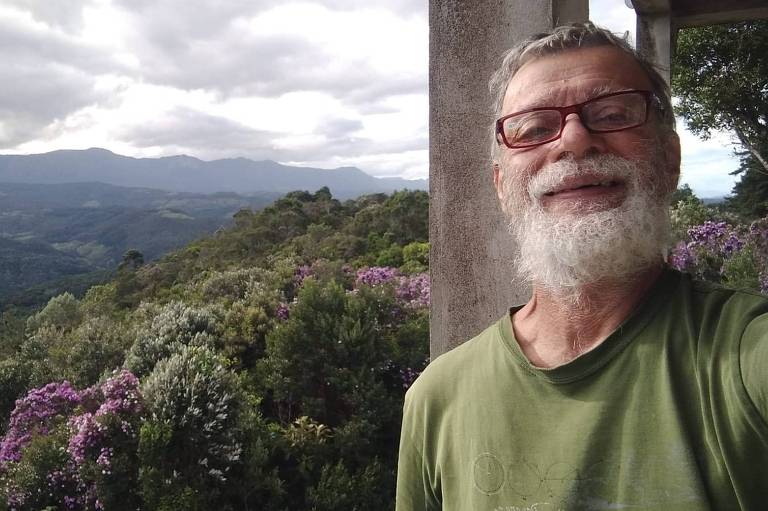 Homem de 69 anos mostra a vista de sua casa para as montanhas da região de Anitápolis