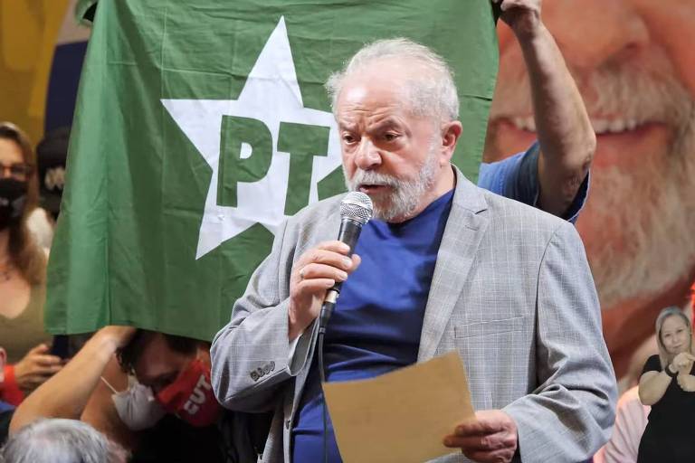 Lula segura microfone e discursa em palco