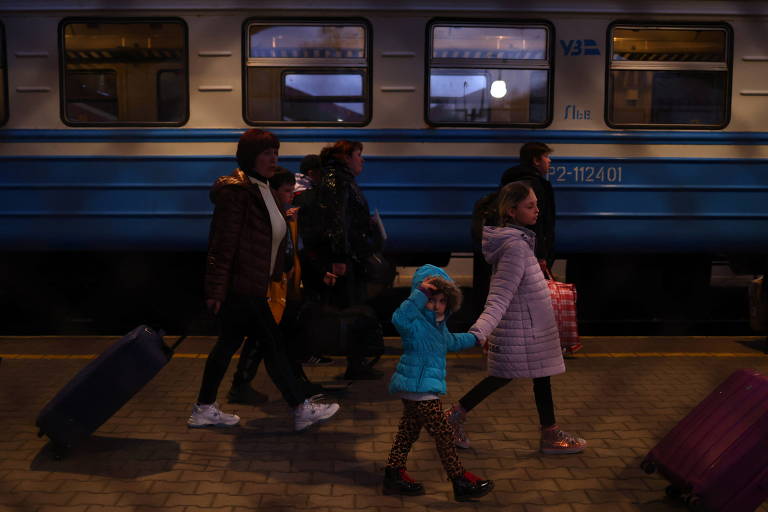 Família com malas e roupas de inverno caminham na plataforma de trem. 