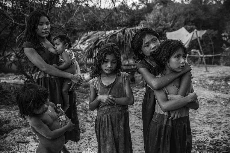 Meninas Pirahã observam motoristas que passam pela rodovia Transamazônica na esperança de receber doações de lanches e refrigerantes, ao lado de seu acampamento às margens do rio Maici, no estado do Amazonas
