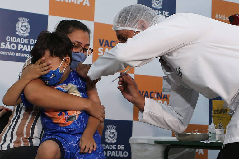 Enfermeiro aplica vacina contra a Covid-19 em braço de menino