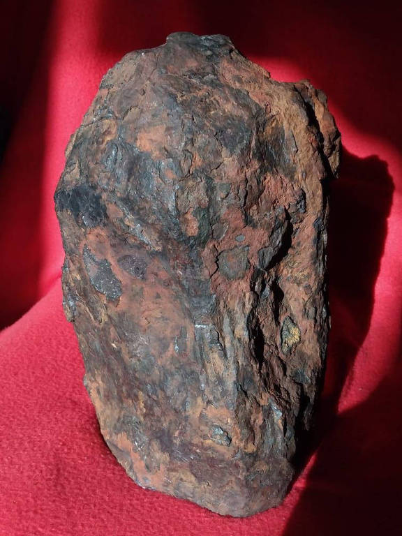 detalhe de meteorito com pano vermelho ao fundo