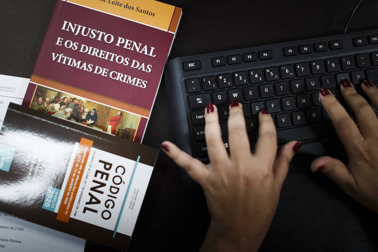 A promotora de Justiça Celeste Leite dos Santos usa computador, ao lado do Código Penal e de livro de sua autoria