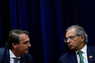 Brazil's President Jair Bolsonaro talks with Brazil's Economy Minister Paulo Guedes during the launch ceremony of the regulatory model of the National Institute of Metrology, Standardization and Industrial Quality (INMETRO) in Brasilia,