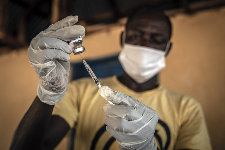 Enfermeiro prepara uma dose da vacina anticovid em Kathantha Yimbo, no norte de Serra Leoa; a falta de notificação de Covid-19 levanta a questão se os recursos para a pandemia deveriam ser usados em outras doenças mais urgentes, como a malária