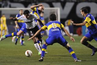 Paulinho of Brazil's Corinthians is challenged by Silva of Argentina's Boca Juniors while Boca Juniors' Caruzzo and Somoza look on during their Copa Libertadores second leg final soccer match in Sao Paulo