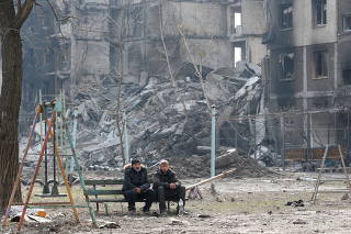 Local residents sit on a bench in the besieged city of Mariupol