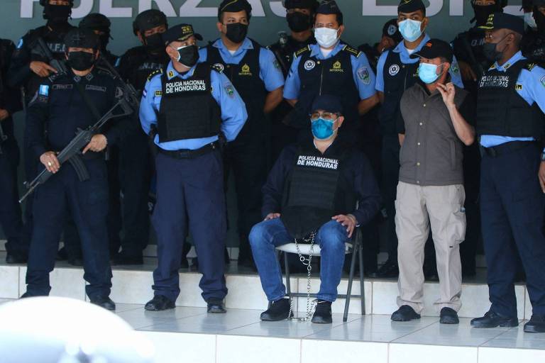 Hernández, ex-presidente de Honduras, sentado de algemas enquanto a polícia do país anunciava detalhes de sua prisão