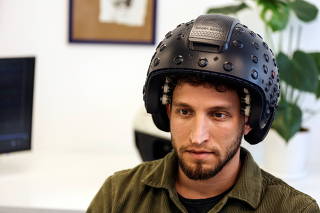 A worker at the Israeli startup Brain.Space demonstrates an EEG enabled helmet, due to be used in an experiment on the impact of a microgravity environment on the brain activity, in Tel Aviv