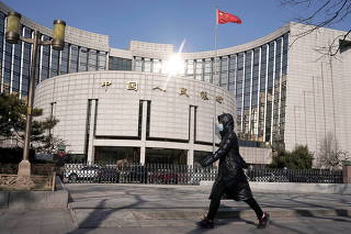 FILE PHOTO: A woman walks past the headquarters of the People's Bank of China, the central bank, in Beijing