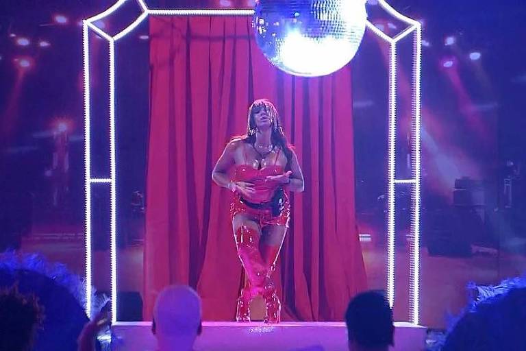 Mulher vestida de vermelho em cima de um palco com globo de discoteca