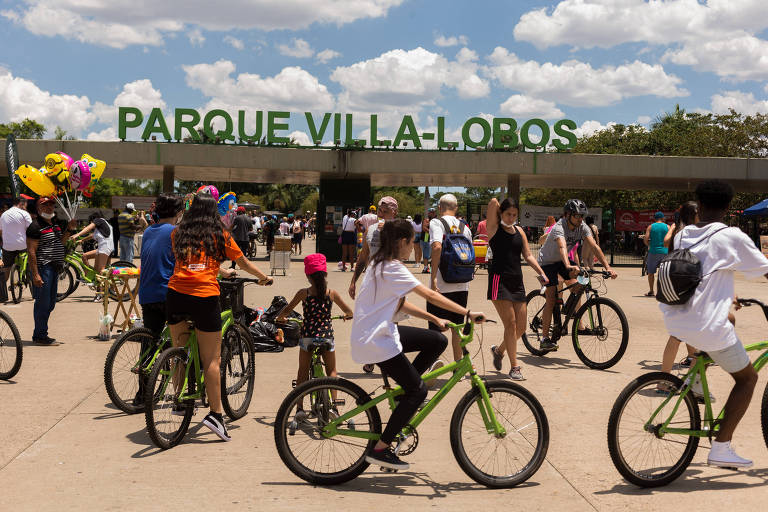 Pessoas com bicicleta em frente ao letreiro do parque
