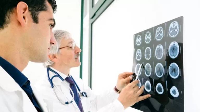 Dois médicos observam radiografia do cérebro de um paciente