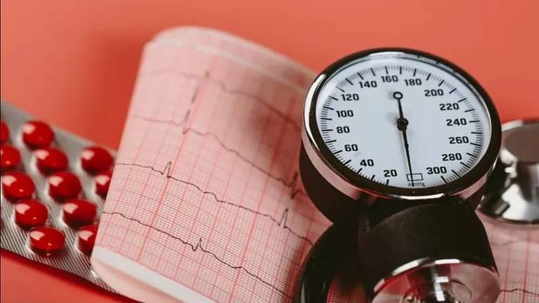 Imagem composta por um medidor de pressão arterial, alguns comprimidos e um gráfico de batimentos cardíacos
