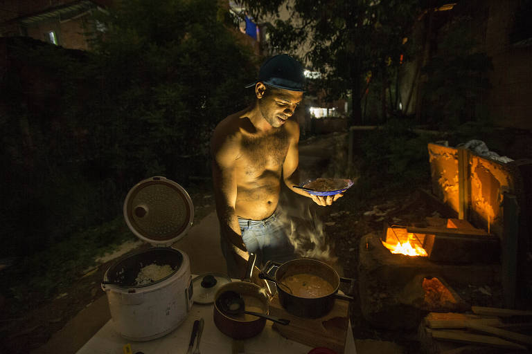 Sergio Rodrigues, técnico de bomba de piscina, serve o jantar feito parte na panela elétrica e parte no fogão a lenha que construiu.