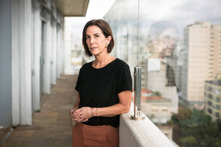 mulher de calça marrom e blusa preta posa em rooftop no centro de São Paulo