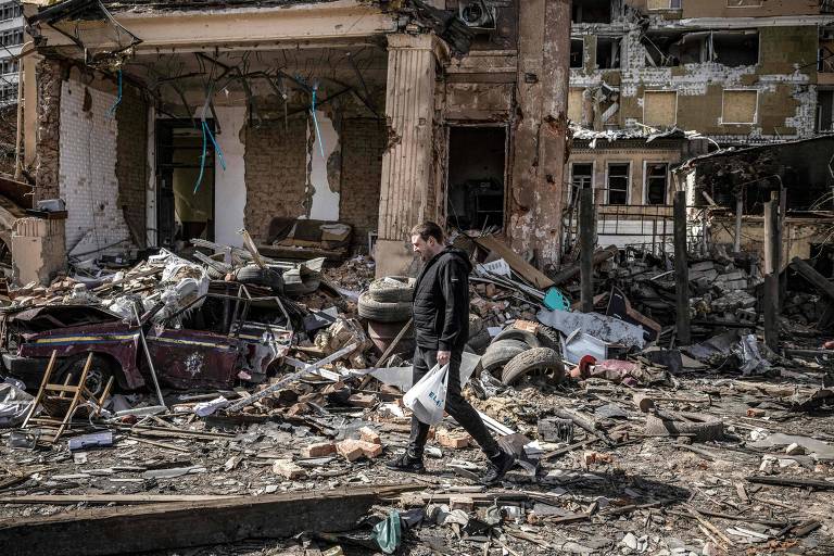 Homem caminha entre destroços de edifício destruído em Kharkiv, na Ucrânia 