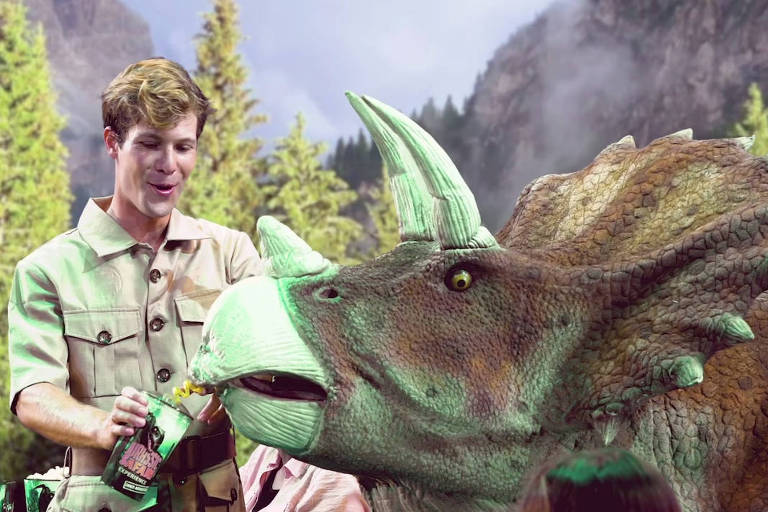 Mike, personagem do espetáculo feito no 'Jurassic Safari - Diner Experience', oferece bebida para um dinossauro