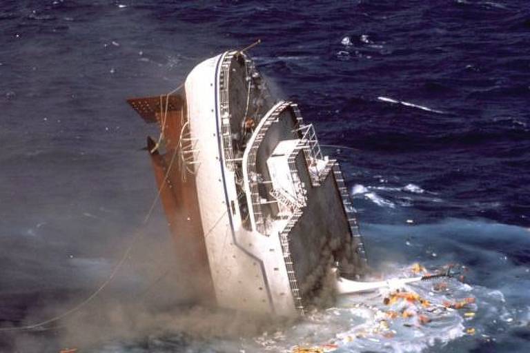 Espreguiçadeiras, coletes salva-vidas e outros detritos caíram do convés e flutuaram na superfície da água antes que o navio finalmente desaparecesse